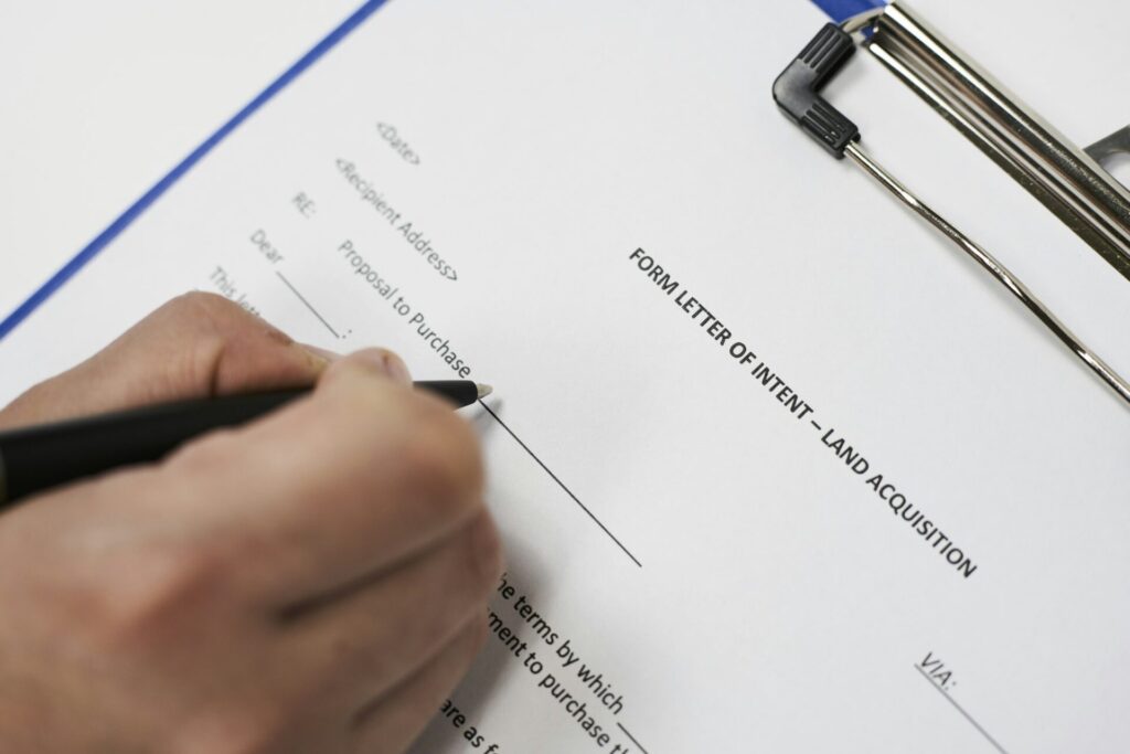 Closeup of a person signing a Form letter of intent for land acquisition
